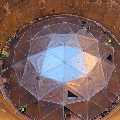 A view from the top of a storage tank looking down on a tank dome in middle of erection